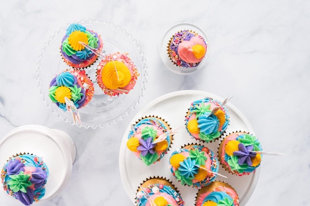 Cupcakes a forma di unicorno con glassa di crema al burro multicolore su supporti per torte.