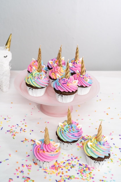 Cupcakes a forma di unicorno decorati con glassa di crema al burro colorata e confettini.