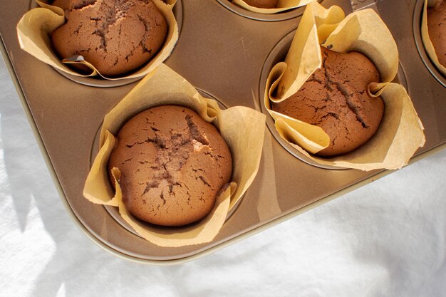 Cupcakes al cioccolato appena sfornati in una teglia su una base bianca