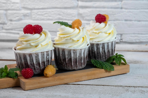 Cupcakes al cioccolato con crema di formaggio e frutti di bosco su un piatto bianco Primo piano