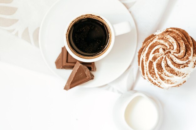 Cupcakes al cioccolato fondente e cioccolato al cacao con una tazza di caffè nero caldo su un tovagliolo verde Spazio per il testo