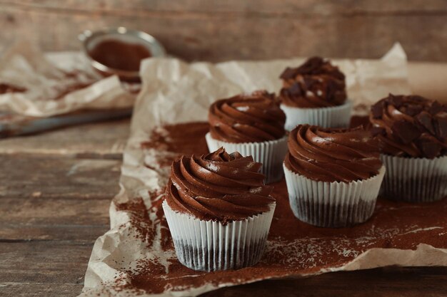 Cupcakes al cioccolato su carta da forno su fondo in legno