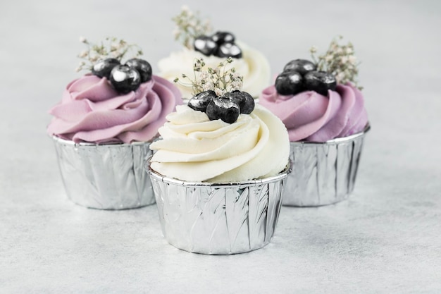 Cupcakes alla vaniglia decorati con glassa di formaggio cremoso e mirtilli freschi su sfondo bianco