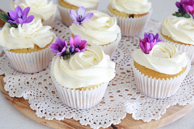 Cupcakes alla vaniglia glassa di fiori di rosa con fiori commestibili viola