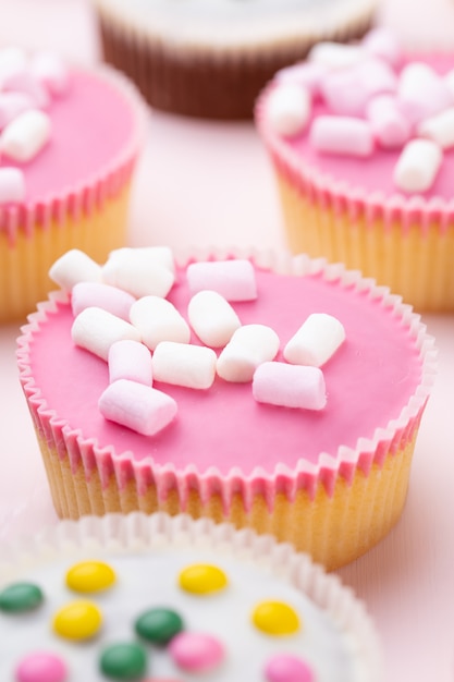 Cupcakes colorati su uno sfondo rosa.