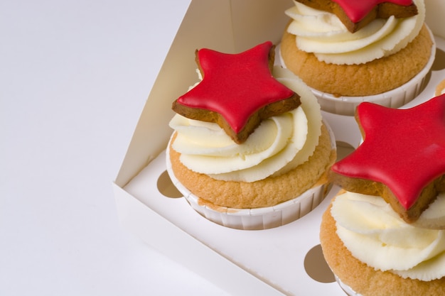 Cupcakes con crema e stelle rosse su sfondo bianco.