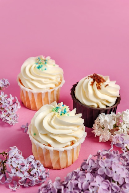 Cupcakes con fiori lilla su un tavolo rosa