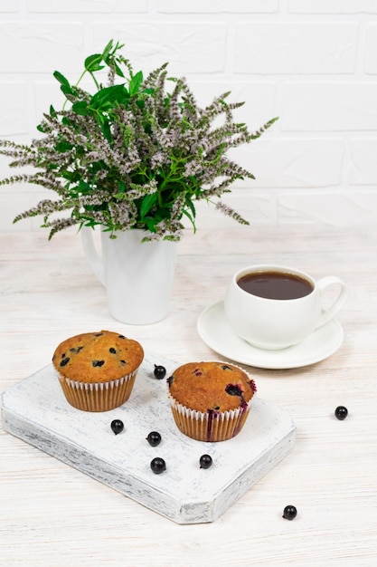 Cupcakes con ribes nero e foglie di menta su un piatto bianco Fuoco selettivo