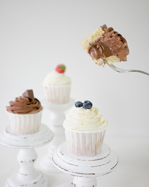 cupcakes con tazze di crema al cioccolato e alla vaniglia su basamenti di torta di legno bianchi