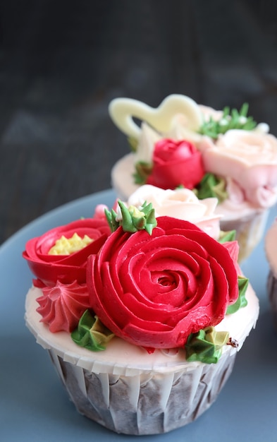 Cupcakes decorati con glassa a forma di fiore rosso su piatto blu chiaro