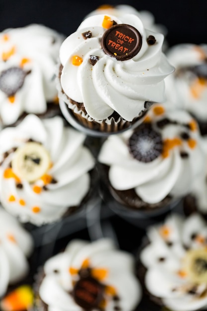 Cupcakes di Halloween al cioccolato con glassa bianca al burro e scaglie di cioccolato sopra.