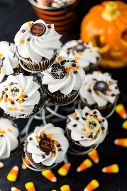 Cupcakes di Halloween al cioccolato con glassa bianca al burro e scaglie di cioccolato sopra.