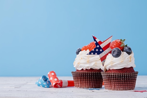 Cupcakes dolci con mirtilli e fragola bandiera usa su sfondo blu