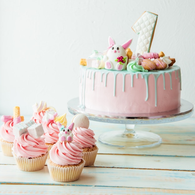 Cupcakes e torta di compleanno rosa di un anno