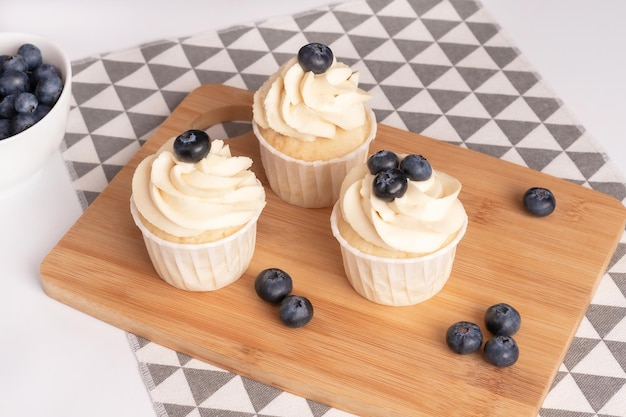Cupcakes fatti in casa con crema di mirtilli e vaniglia su tavola di legno Primo piano