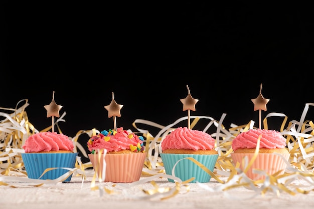 Cupcakes festivi con candele a forma di stelle su sfondo nero. Copia spazio. Torte fatte in casa.