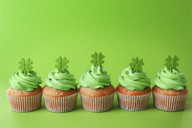Cupcakes gustosi con trifoglio su sfondo verde Concetto del giorno di San Patrizio
