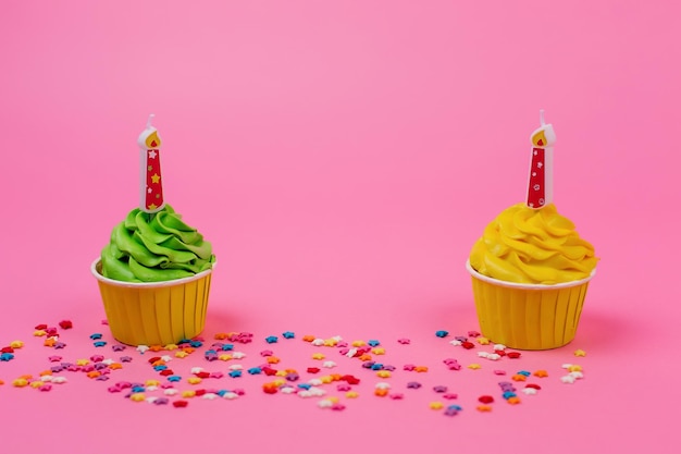 Cupcakes multicolori con candele su uno sfondo rosa posto per l'iscrizione