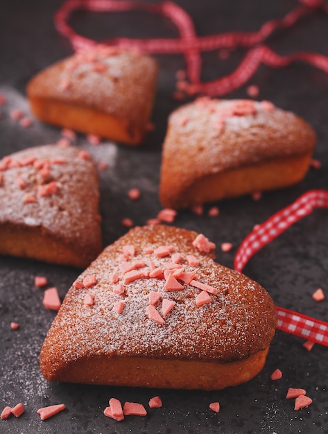 Cupcakes nel cuore con zucchero a velo su sfondo nero