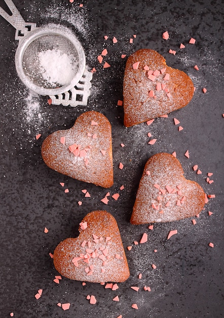 Cupcakes nel cuore con zucchero a velo su sfondo nero