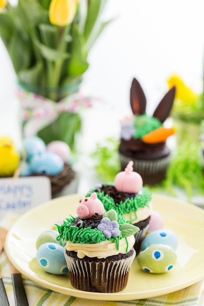 Cupcakes pasquali al cioccolato decorati con orecchie da porcellino e da coniglio.