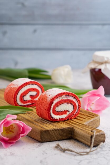 Cupcakes rosa fatti in casa su tavola di legno con tulipani primaverili e vasetto di marmellata su sfondo grigio