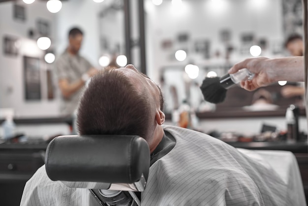 Cura dei capelli. Acconciature da uomo nei saloni di parrucchiere. Il barbiere fa un taglio di capelli e la barba al suo cliente.