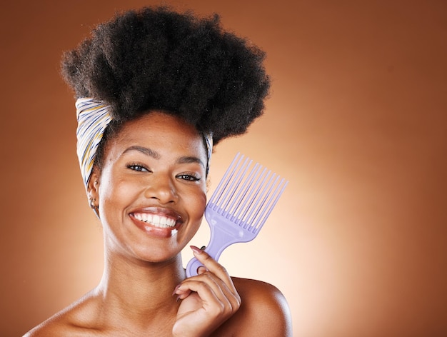 Cura dei capelli bellezza e donna nera con pettine afro per una routine in studio con spazio mockup Sorriso felice e ritratto di giovane modella africana con capelli naturali e prodotto isolato da sfondo marrone