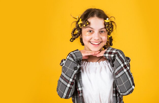 Cura dei capelli per il bambino. piccola donna che governa con il rullo per capelli. cerotto per terapia oculare. bellezza e moda. piccola ragazza ha papillotes capelli. parrucchiere per bambini. acconciatura lunga sana. creazione di riccioli pin.