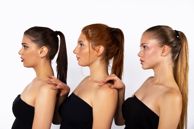 Cura del corpo. Tre ragazze belle e attraenti stanno posando su un muro bianco e guardano tutte in una direzione. Spa e concetto di bellezza. Foto di alta qualità