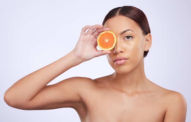 Cura della pelle arancione e ritratto di donna in studio per il trattamento di vitamina c e cosmetici su sfondo viola Modello di frutta e ragazza del viso rilassati con disintossicazione facciale organica o della pelle fai da te con pulizia agli agrumi