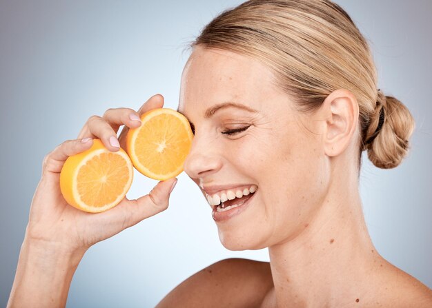 Cura della pelle bellezza e donna con arancia in studio per spa wellness dermatologia e trattamento viso Cosmetici alla vitamina c e ragazza felice con frutta per prodotti di bellezza naturali sani e biologici