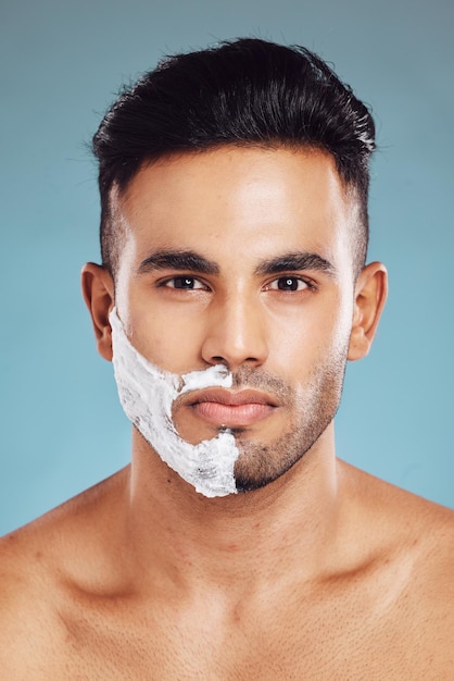 Cura della pelle del ritratto e rasatura dell'uomo in studio su sfondo blu per la cura dei peli del viso in India Prodotti sani e modello di viso giovane rade barba e baffi nella routine di cura di sé con crema