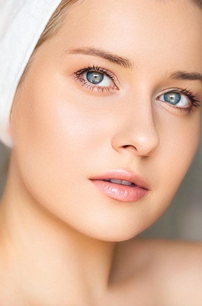 Cura della pelle e routine di bellezza Bella donna con asciugamano bianco avvolto intorno ai cosmetici per la cura della pelle della testa e alla cosmetologia del viso