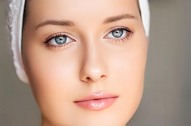 Cura della pelle e routine di bellezza Bella donna con asciugamano bianco avvolto intorno ai cosmetici per la cura della pelle della testa e alla cosmetologia del viso