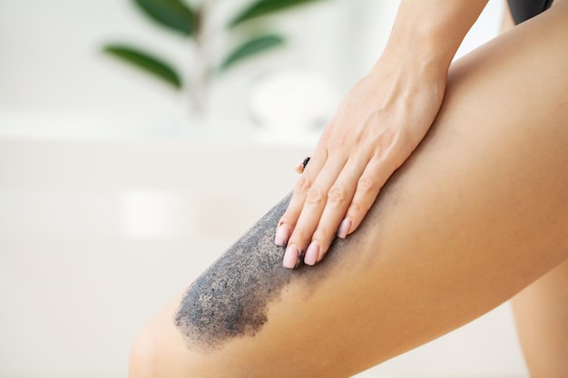 Cura della pelle, la donna applica uno scrub nero con sale marino.