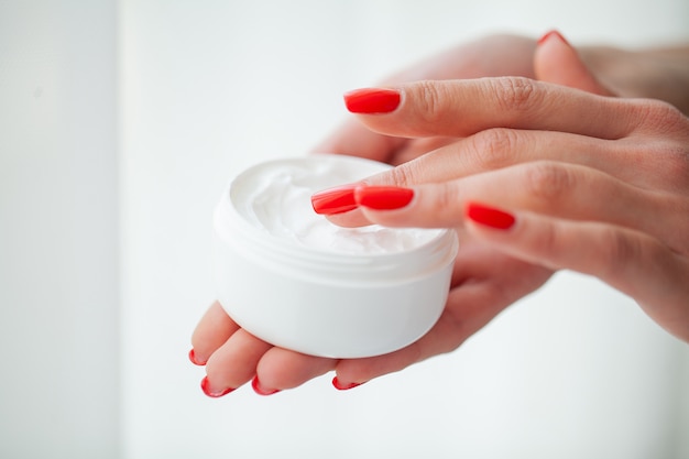 Cura della pelle, mani di bella donna con crema