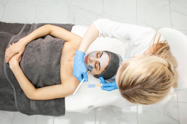 Cura della pelle professionale nella clinica di cosmetologia, il medico dermatologo applica la crema con il pennello