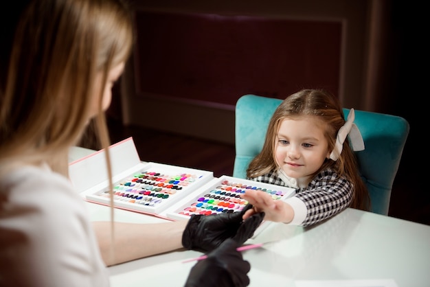 Cura delle mani nel salone per una bambina la sera.