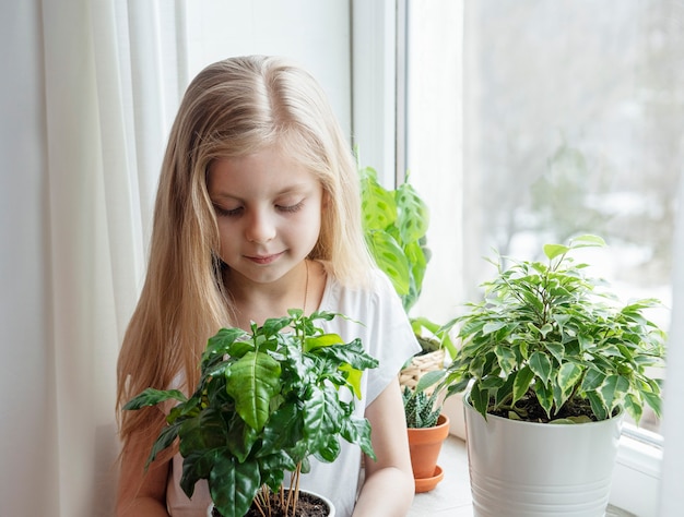 Cura delle piante d'appartamento, bambina che si prende cura delle piante d'appartamento