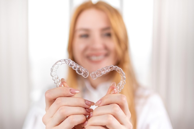 Cura dentaleRagazza sorridente con i capelli rossi che tiene gli allineatori a forma di cuore