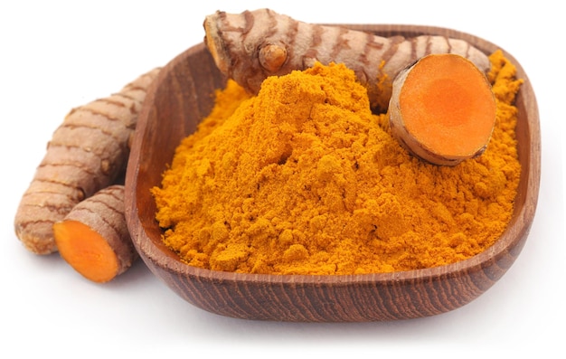 Curcuma cruda con polvere in una ciotola su sfondo bianco