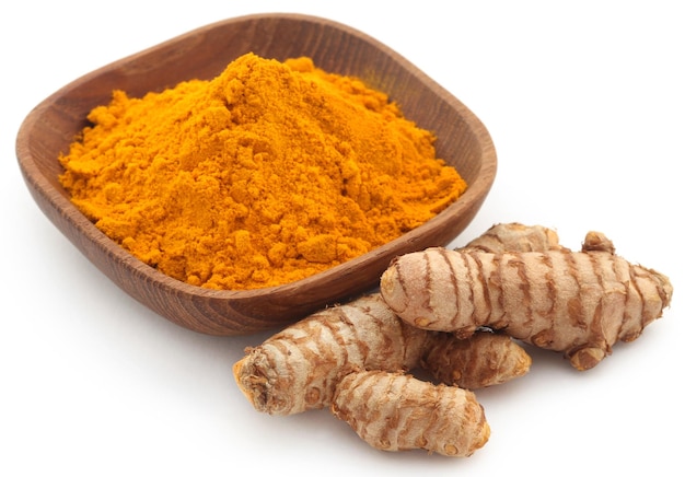 Curcuma cruda con polvere in una piccola ciotola su sfondo bianco