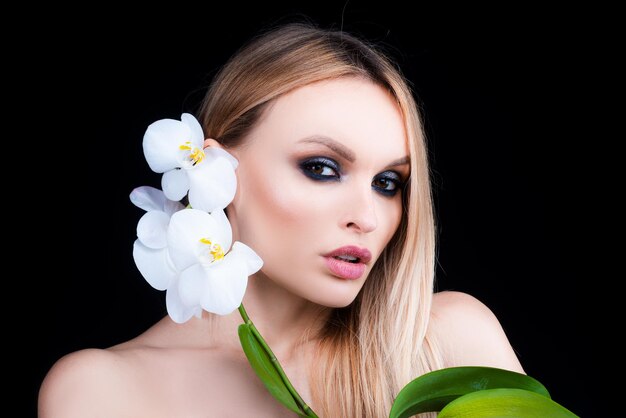 Cure di bellezza. Prodotti cosmetici. Donna con fiore di orchidea.