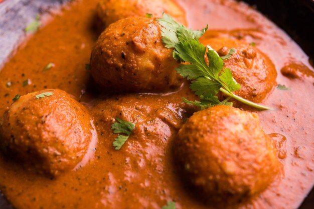 Curry di patate speziato appena cucinato in padella o Dum aloo caldo e piccante servito con tandoori roti o naan o pane indiano o chapati e insalata verde, messa a fuoco selettiva