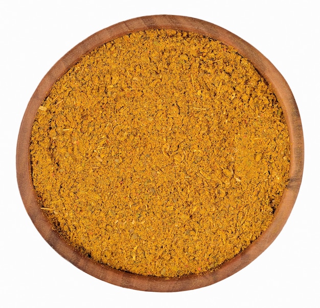 Curry in polvere in una ciotola di legno su sfondo bianco