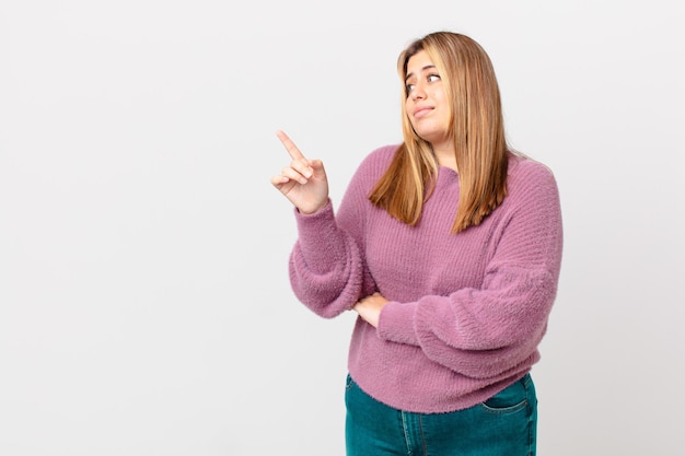 Curvy bella donna bionda che alza le spalle, sentendosi confusa e incerta