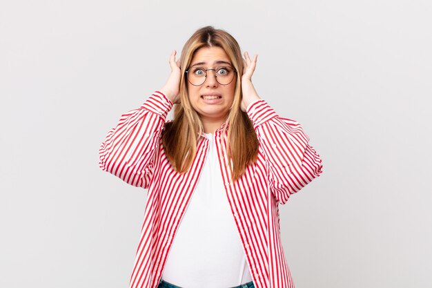 Curvy bella donna bionda che si sente stressata, ansiosa o spaventata, con le mani sulla testa