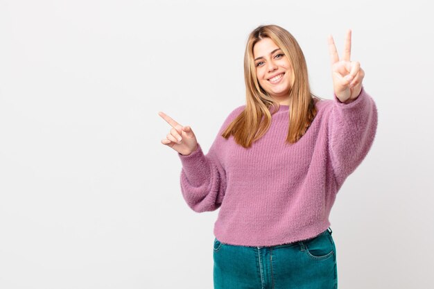 Curvy bella donna bionda che sorride e sembra amichevole, mostrando il numero due