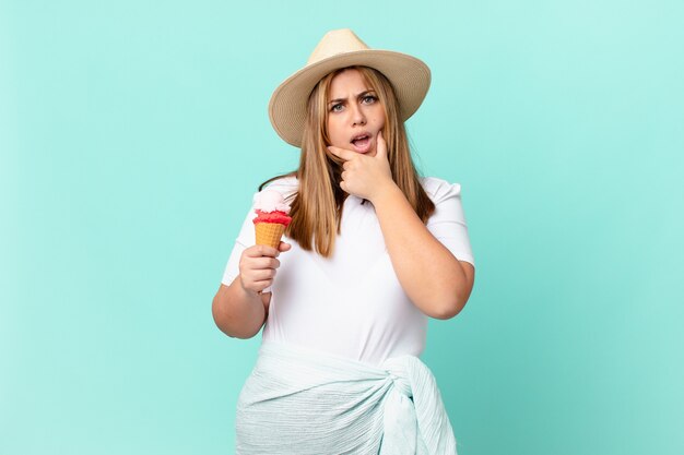 Curvy bella donna bionda con la bocca e gli occhi spalancati e la mano sul mento